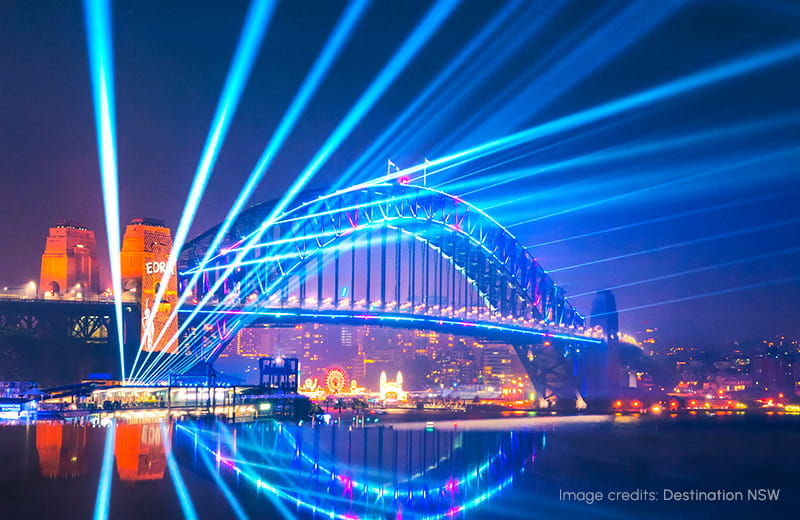 Sydney Harbour reflects the vibrant projections on the Harbour Bridge during Vivid Sydney