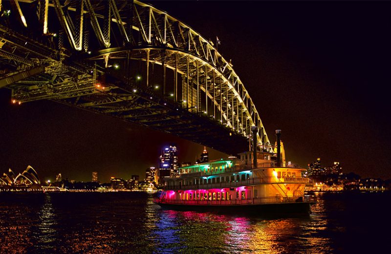Sydney Showboat passing under the Sydney Harbour Bridge at night