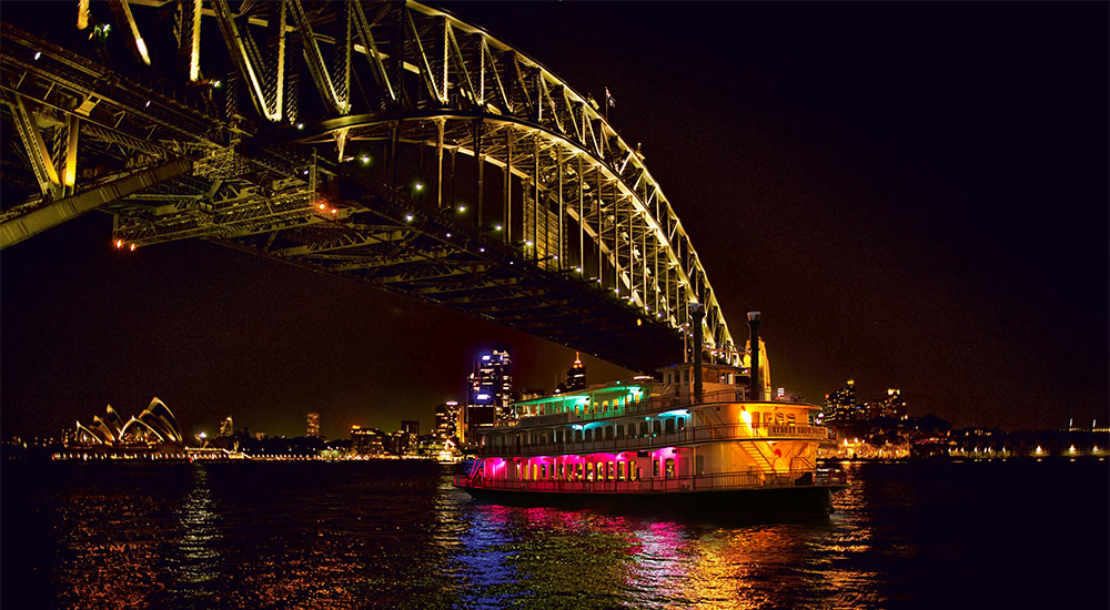 Sydney Showboat passing under the Sydney Harbour Bridge at night