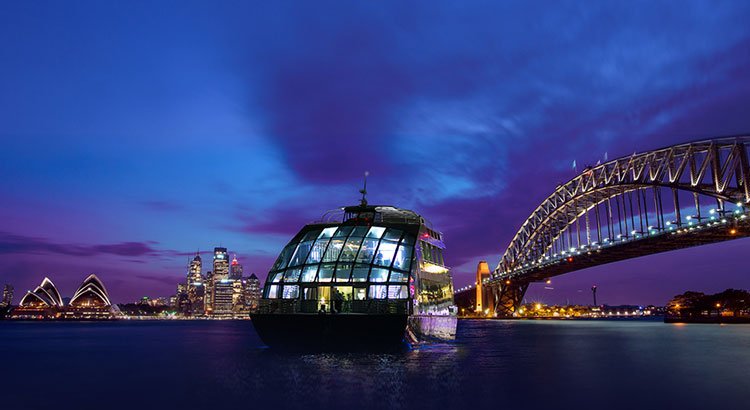Splendour of a glass boat at night– a purple blue sky, serene waters with splendid harbour views